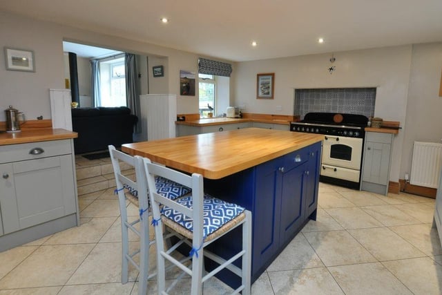 The spacious country style kitchen has a central island and fitted units with oak worktops.