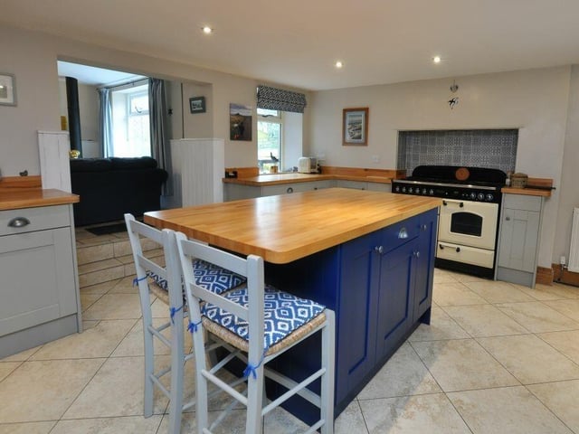 The spacious country style kitchen has a central island and fitted units with oak worktops.