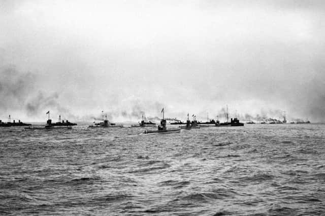 A flotilla of German submarines (U-Boats) and torpedo boats heading out to sea.