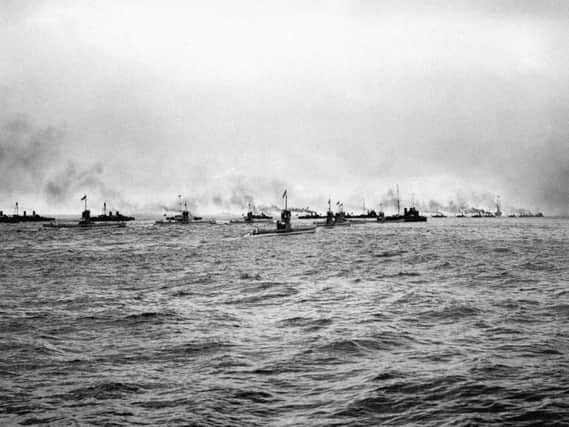 A flotilla of German submarines (U-Boats) and torpedo boats heading out to sea.