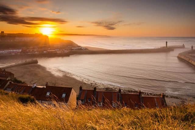 Whitby Harbour as the sun goes down shining through the sea mist held back by the cliffs of Sandsend