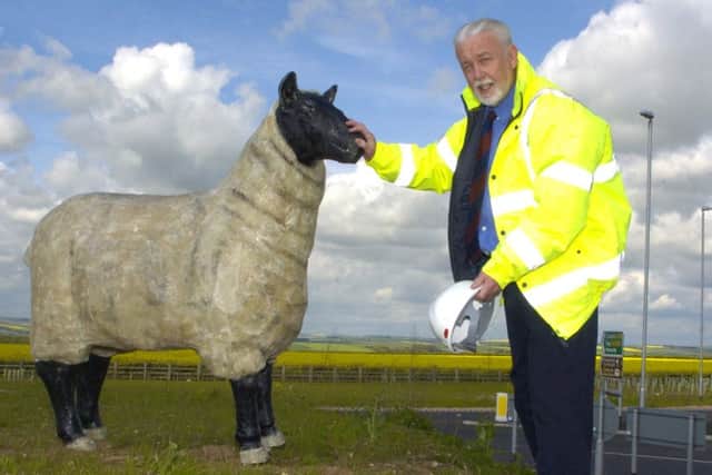 Ronald Falck with one of the sheep sculptures he put on the Dotterel roundabout