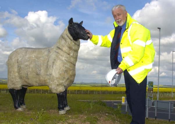 Ronald Falck with one of the sheep sculptures he put on the Dotterel roundabout