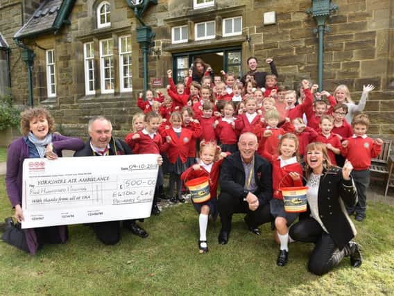 Yorkshire Air Ambulance get a cheque from Egton School. Head Liz Orland, Kevin Hutchinson of the Air Ambulance, Bea Grenfell, Ex Air Ambulance Pilot Andy Hall, Bonnie Grenfell and Mum Vicky cheer with the school children. Picture by Richard Ponter rp184315