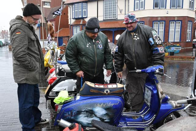 People admire each other's scooters in the rain