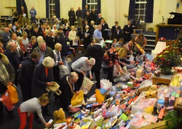 Members of the congregation bring their toys and gifts to the carols and toys service.