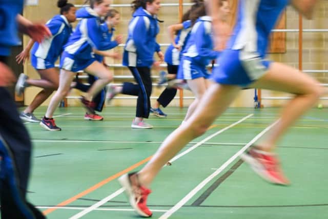 Students run during a Physical Education (PE) lesson inside the gymnasium sports hall.