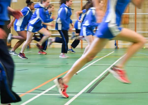 Students run during a Physical Education (PE) lesson inside the gymnasium sports hall.