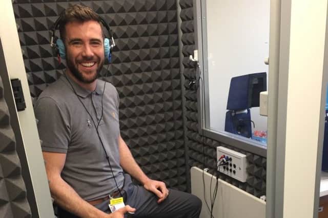 Senior Audiologist Alex Trousdale demonstrates the new soundproof booth
