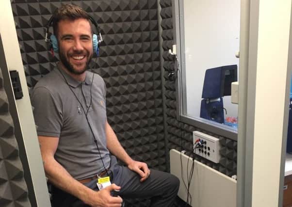 Senior Audiologist Alex Trousdale demonstrates the new soundproof booth