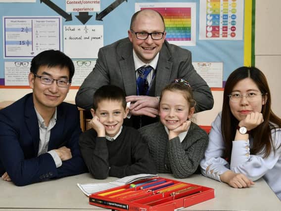 Teachers Lu Yong and Chen Jiajun do some class work with pupils Noah Simpson and Ruth Davis. Also pictured, teacher Matthew Davies who liaised with the visiting teachers.