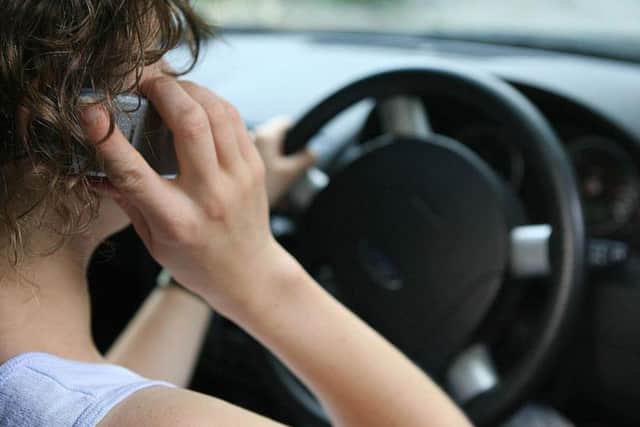 File photo of a woman using a mobile phone while driving as fiercer fines are failing to stop motorists using hand-held mobile phones while driving, figures show