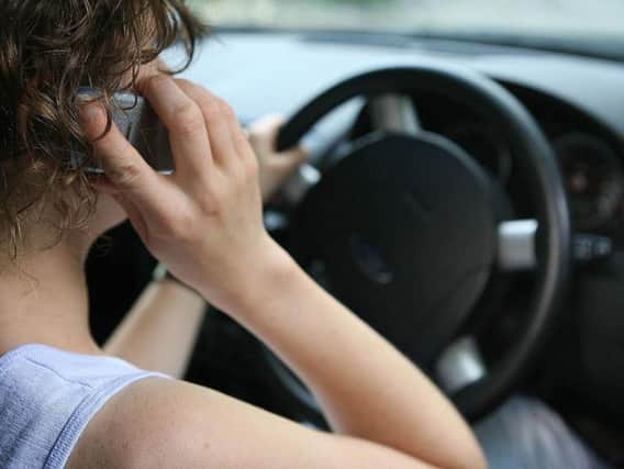 File photo of a woman using a mobile phone while driving as fiercer fines are failing to stop motorists using hand-held mobile phones while driving, figures show