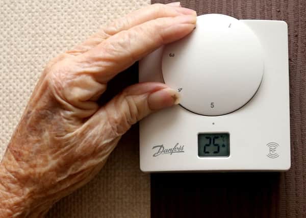 An elderly lady adjusting her thermostat on at home.