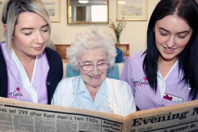 Gloria Walker, a resident at Normanby House, reads the news from July 1985 with care assistants Trudi Hewitt, left and Laura Cambleman.