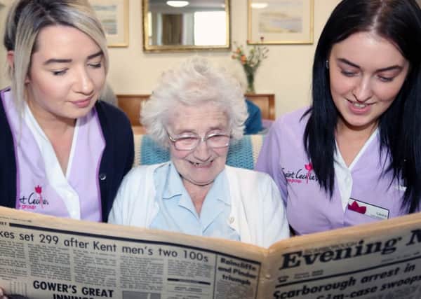 Gloria Walker, a resident at Normanby House, reads the news from July 1985 with care assistants Trudi Hewitt, left and Laura Cambleman.