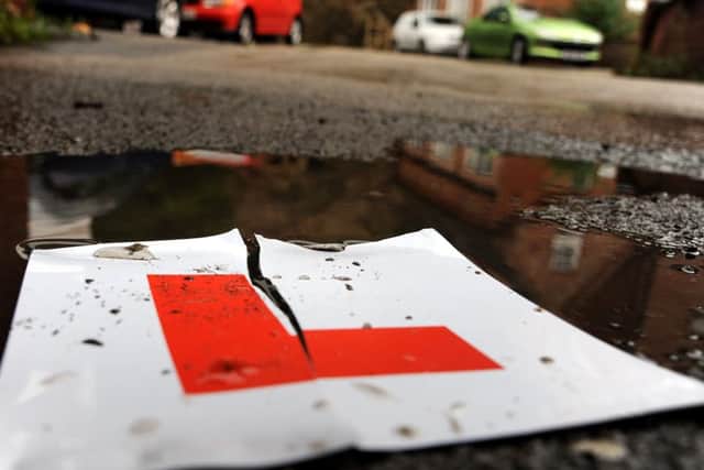 A torn L plate lies on the ground