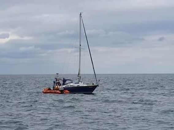 The inshore boast crew trying to cut the yacht free from the fishing gear. PIC: Filey Lifeboat