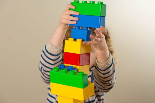 A preschool age child plays with plastic building blocks.
