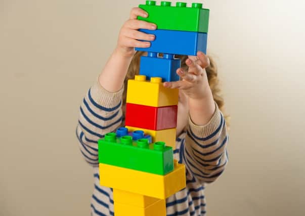 A preschool age child plays with plastic building blocks.