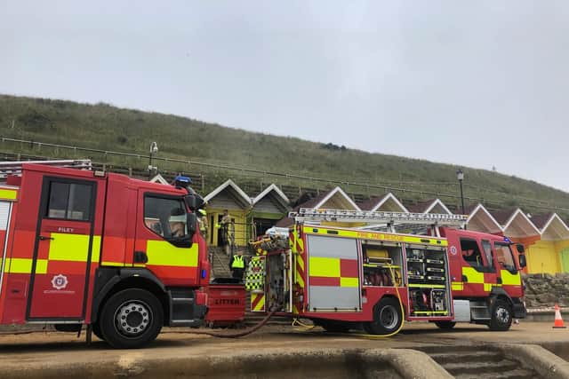 Fire crews at the scene - the fire damaged chalets are on the row behind.