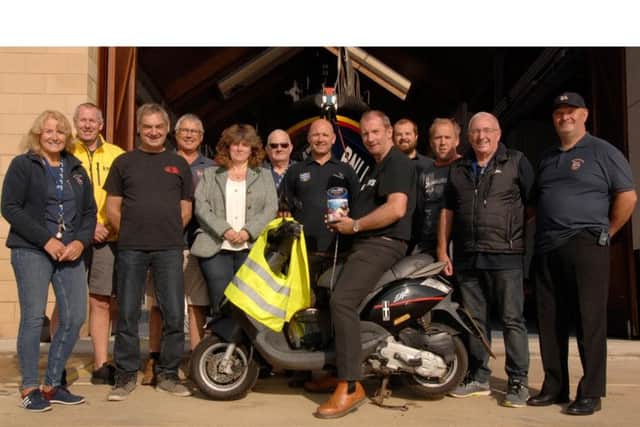 Col on the moped presenting the funds he raised to Scarborough RNLI. PIC: RNLI