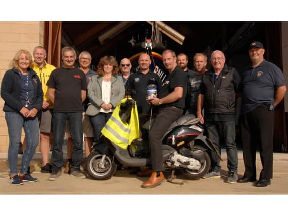Col on the moped presenting the funds he raised to Scarborough RNLI. PIC: RNLI