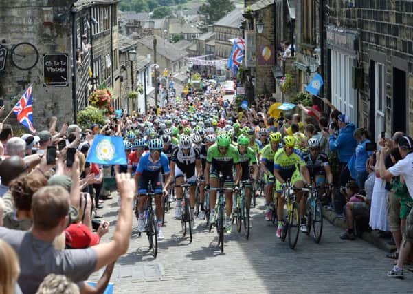 File photo dated 06-07-2014 of The peloton rides up Main Street as stage two of the Tour de France passes through Haworth. PRESS ASSOCIATION Photo. Issue date: Tuesday October16, 2014. The 101st Tour de France began in Leeds with a Grand Depart billed as the best ever. Expectations were matched as 4.8million people lined the road side from Leeds to Harrogate, York to Sheffield and then Cambridge to London. Yorkshire was bathed in sunshine as the peloton rode through Haworth. See PA story SPORT Christmas Gallery. Photo credit should read Martin Rickett/PA Wire.