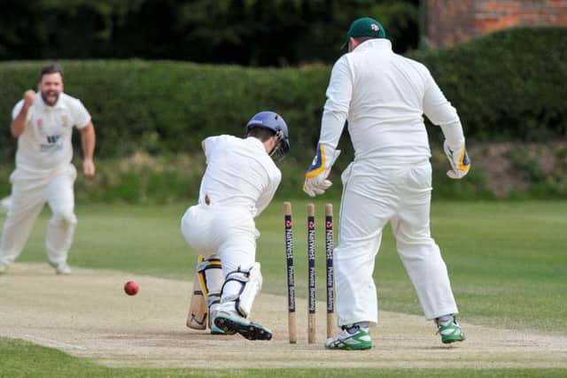 CRICKET --- Flixton CC vs. Malton, played at Flixton. // Malton batsman Shaun Harland is bowled out by Chris Mann (left). Pictured with Flixton wicket keeper Anthony Stones. Saturday 11th July 2015. HARRY ATKINSON