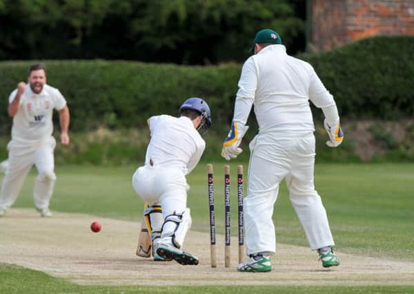 CRICKET --- Flixton CC vs. Malton, played at Flixton. // Malton batsman Shaun Harland is bowled out by Chris Mann (left). Pictured with Flixton wicket keeper Anthony Stones. Saturday 11th July 2015. HARRY ATKINSON