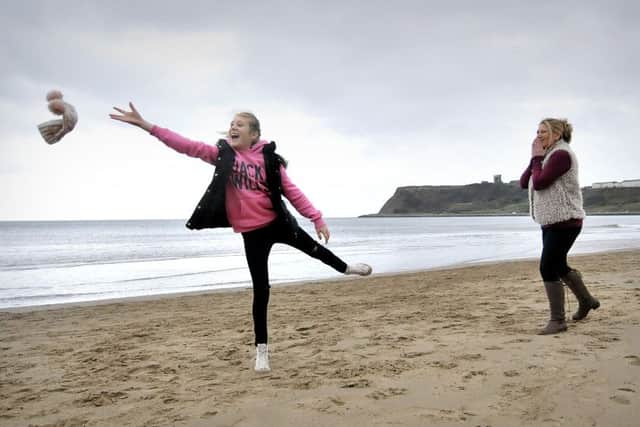 Enjoying a walk on a very windy North Bay in Scarborough . Megan loses her hat as Mum Nicki Thackeray laughs as the hat soars skywards. pic Richard Ponter 155212a