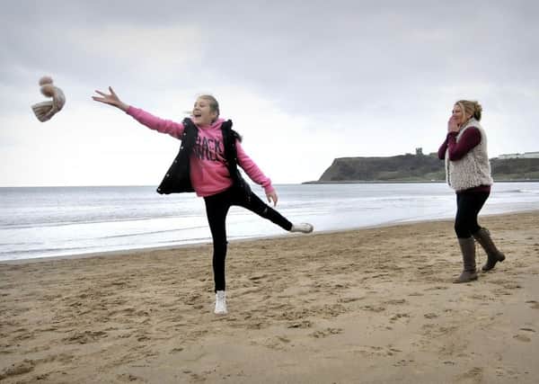 Enjoying a walk on a very windy North Bay in Scarborough . Megan loses her hat as Mum Nicki Thackeray  laughs as the hat soars skywards. pic Richard Ponter 155212a