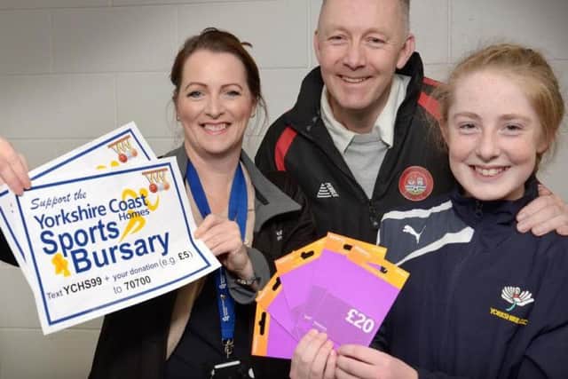 Twelve year old Whitby cricketer Daisy Stokoe (right) and her dad Jon (centre) receive their Yorkshire Coast Homes Sports Bursary support, in the form of 100 worth of Sainsbury vouchers for the purchase of fuel, from YCH staff member Helen Swinger (left).