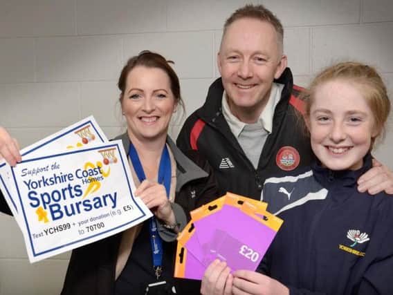 Twelve year old Whitby cricketer Daisy Stokoe (right) and her dad Jon (centre) receive their Yorkshire Coast Homes Sports Bursary support, in the form of 100 worth of Sainsbury vouchers for the purchase of fuel, from YCH staff member Helen Swinger (left).