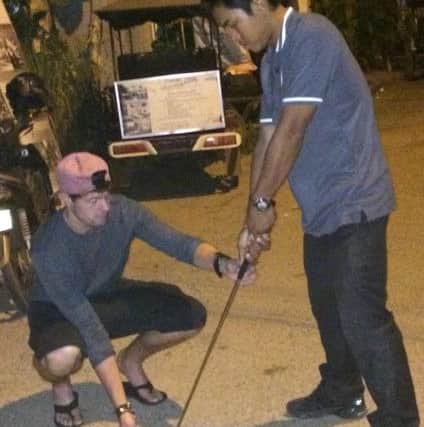 Alex Belt teaching a local in the street in front of his tuk tuk.