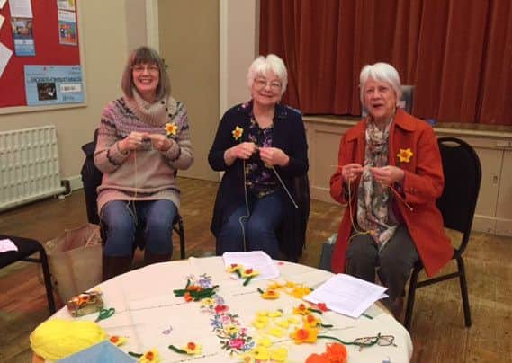 Glynis Francis (red coat) and others knitting daffodils to help Marie Curie