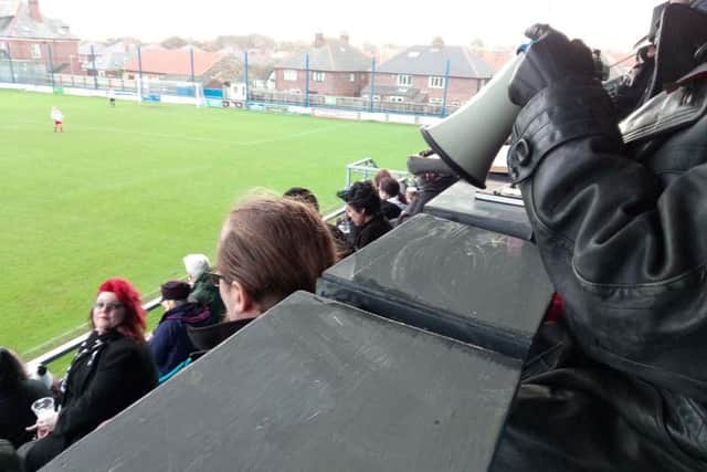 One of the commentator's pints is blown over in the strong wind.