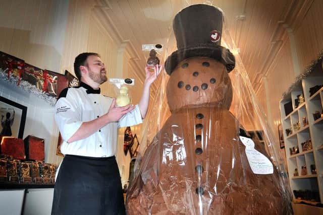 Chocolatier Alex Grant of Crofts in Scarborough admires his festive charity chocolate snowman in his shop.