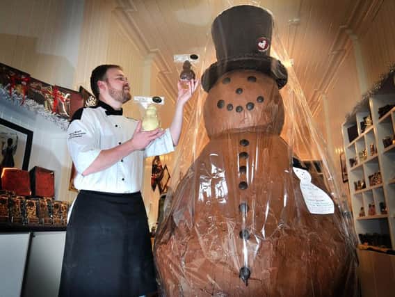 Chocolatier Alex Grant of Crofts in Scarborough admires his festive charity chocolate snowman in his shop.
