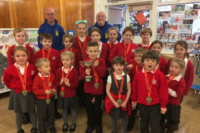 Harry and Ralph from Scarborough Athletics Club with Heslerton Primary School pupils. The Small Schools trophy held by Louie Spencer, 6.