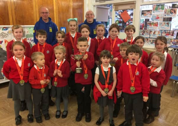 Harry and Ralph from Scarborough Athletics Club with Heslerton Primary School pupils. The Small Schools trophy held by Louie Spencer, 6.