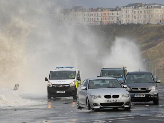 Cars dodge the waves before the road was closed off.
