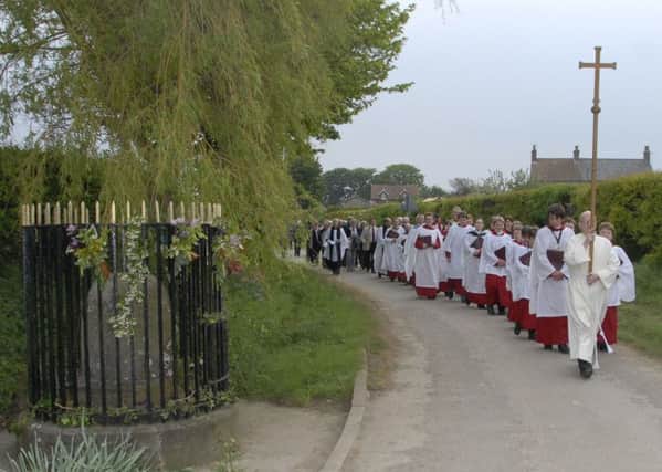 A procession heads towards Harpham well for the well dressing ceremony.