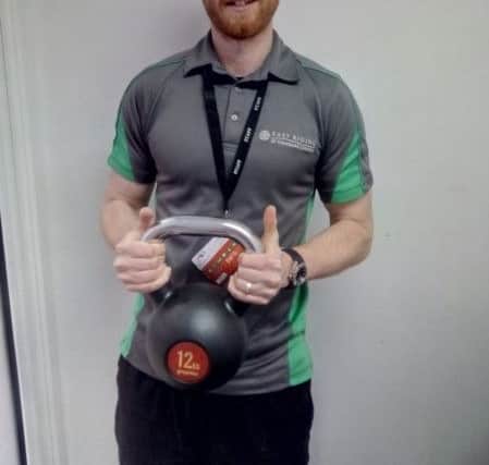 Danny Moore holds a kettlebell which shows how much weight the Reluctant Runner has shed so far