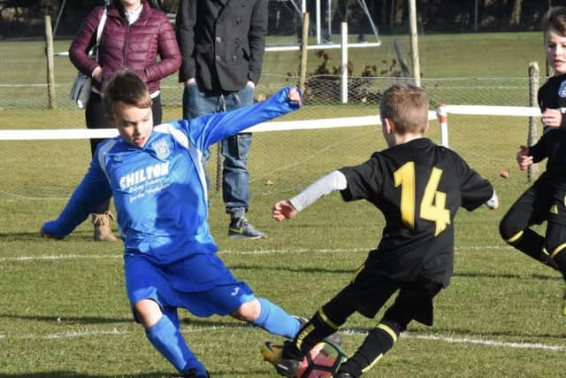 Scalby Under-Eights challenge Heslerton (blue kit) for the ball