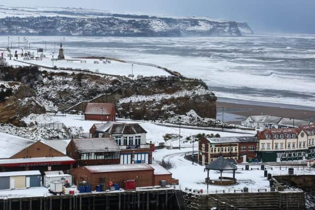 The view towards Whitby's west cliff with the famous whalebones and Captain Cook statue is covered in snow, with Sandsend in the distance.