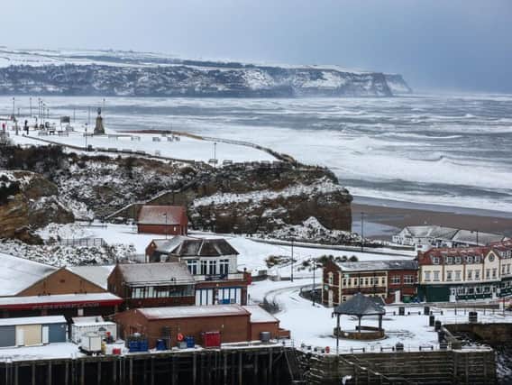 The view towards Whitby's west cliff with the famous whalebones and Captain Cook statue is covered in snow, with Sandsend in the distance.