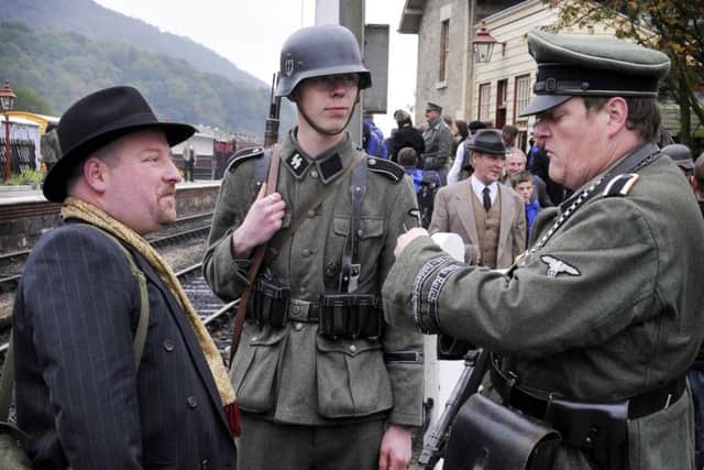 German re-enactors stop a passenger to check his ticket during North Yorkshire Moors Railway Wartime Weekend event at Levisham Station.