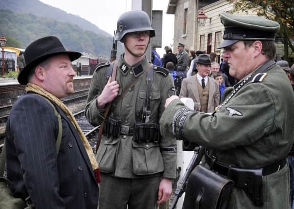German re-enactors stop a passenger to check his ticket during North Yorkshire Moors Railway Wartime Weekend event at Levisham Station.